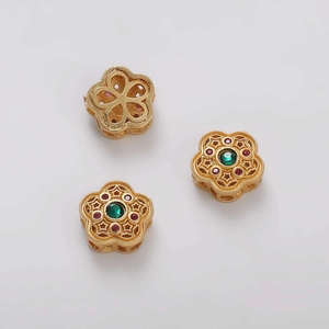 Detalle de cuentas florales doradas con piedras verdes y rojas para creación de joyería