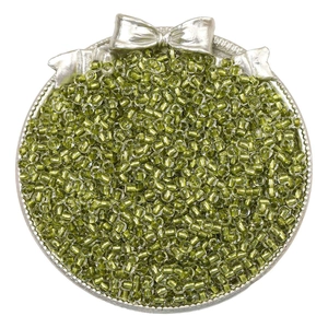Macro detail of olive green transparent glass seed beads in a silver decorative tray
