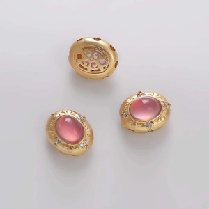 Vista macro detallada de dije ovalado dorado con circón rosa y reverso calado fino