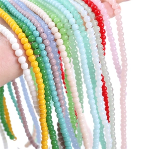 Hand holding multiple colorful 4mm glass round beads for DIY handmade jewelry crafts