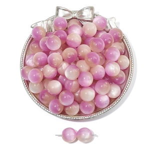 Macro detail of gradient pink resin cat eye beads in a decorative silver tray