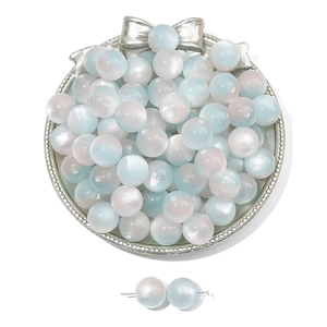 Detailed view of gradient blue and white resin cat eye beads on a silver bow tray