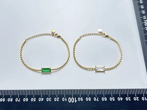 Detailed macro view of gold plated square cut green emerald and zircon cubic bracelets