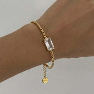 Close-up of golden stainless steel bracelet with rectangular zircon on woman's wrist