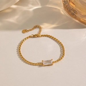 Detailed macro view of golden twisted rope chain bracelet with large square zircon stone