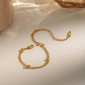 Détail d'un bracelet double rang à perles dorées avec fermoir mousqueton et extension