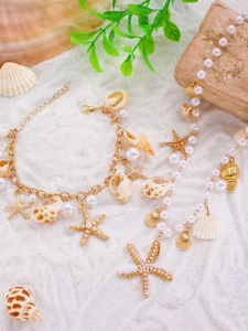 Detail of seashell necklace and bracelet set with pearls on white beach sand background