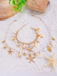 Detail of seashell and starfish charms on a gold chain necklace and bracelet set