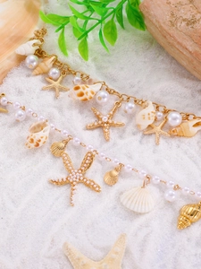 Detail of beach style bracelet with gold starfish, white pearls and natural shells