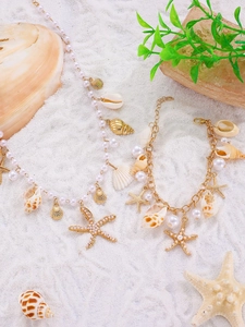 Detailed beach jewelry set featuring starfish and seashell charms on white fine sand