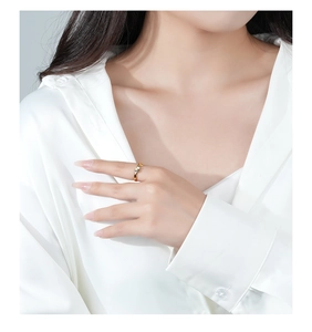 Close-up of wavy gold ring with three sparkling clear stones on a hand model