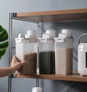 Three transparent grain storage containers with lids and scales on wooden shelf