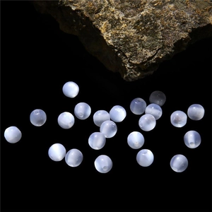 Macro shot of translucent light blue resin cat eye beads on a dark background
