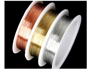 Three spools of copper, gold and silver craft wire for DIY jewelry making on black background