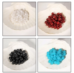 Vue macro de perles acryliques rondes en blanc, rouge, noir et bleu pour bijoux artisanaux
