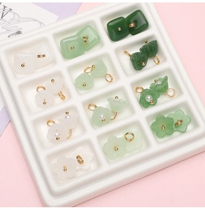 Detailed close-up of DIY flower charms and green jade-style pendants in a sorting tray