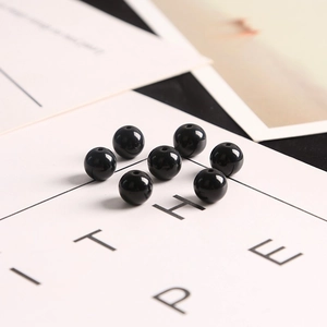 High-polished black glass round loose beads set on minimalist card for DIY jewelry
