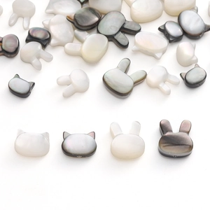 Détail de perles artisanales en nacre naturelle en forme de tête de chat et de lapin