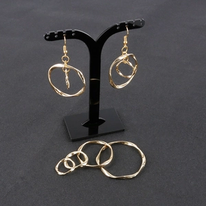Golden alloy twisted circle earrings and DIY jewelry components on a black display stand