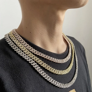 Détail de trois chaînes cubaines glacées superposées en or rose, or et argent