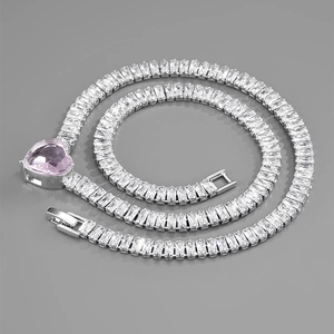 Macro detail of silver-tone cuban chain with clear zircons and pink heart-shaped pendant