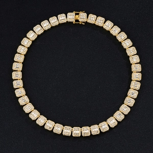 Chaîne cubaine dorée 12mm avec cristaux taille baguette sur fond noir texturé élégant