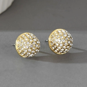 Gros plan de boucles d'oreilles boules dorées ornées de strass blancs scintillants
