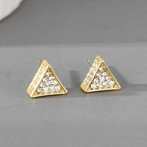 Vue macro de boucles d'oreilles triangulaires dorées ornées de strass étincelants