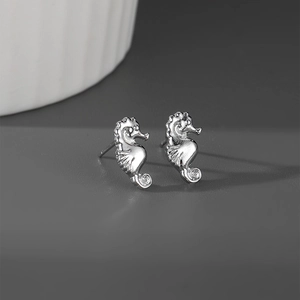 Détail macro de boucles d'oreilles hippocampe en argent avec textures sur fond mat
