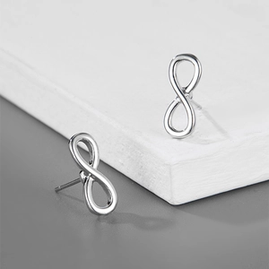 Vue détaillée de boucles d'oreilles clous infini en argent poli pour hommes sur pierre