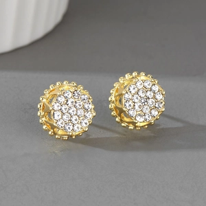 Gros plan sur boucles d'oreilles boules dorées hip-hop avec strass blancs et motifs ajourés