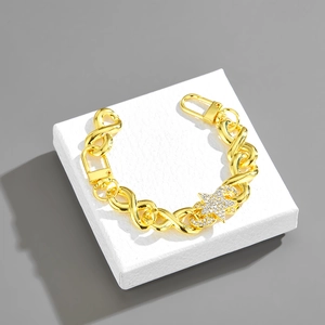 Detail of gold-tone infinity link chain featuring a sparkling pavé star pendant
