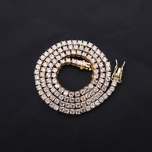 Detailed close-up of a gold-toned tennis chain with sparkling cubic zirconia and a box clasp