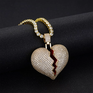 Dettaglio di un ciondolo a cuore spezzato dorato con zirconi su una catena tennis abbinata