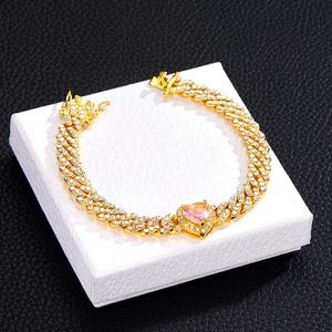 Makroaufnahme von Hip-Hop-Panzerarmband mit rosa Herz-Edelstein auf weißem Sockel