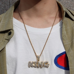 Nahaufnahme einer Hip-Hop-Goldseilkette mit eisigem KING-Anhänger an einem männlichen Model