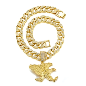 Detailaufnahme des goldenen Adler-Anhängers mit weißen Kristallen an einer Panzerkette