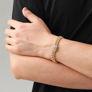 Macro shot of gold-plated iced-out Cuban chain bracelet with crystal heart charm