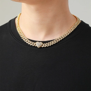 Macro shot of gold-plated iced-out Cuban link chain featuring a sparkling heart pendant
