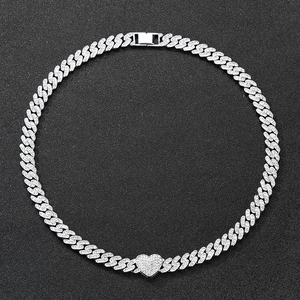 Macro shot of a silver iced-out Cuban chain necklace with a sparkling heart pendant