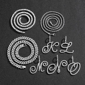 Detail view of silver iced-out hip hop necklaces with cursive letter pendants on black background