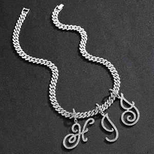 Macro shot of silver Cuban link chain with iced out cursive H I D letter pendants