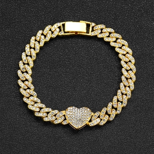 Macro shot of 9mm gold Cuban link bracelet with iced out heart pendant and clasp