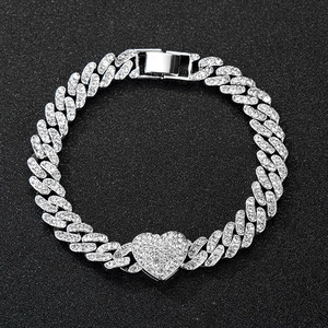 Detail of silver Cuban link chain with an iced-out rhinestone heart pendant and clasp