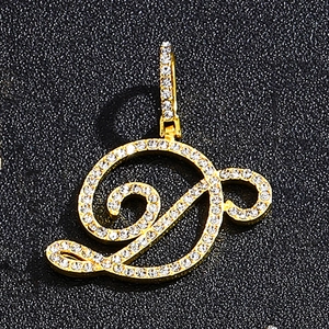 Macro view of gold-tone iced out letter D pendant with sparkling cubic zirconia