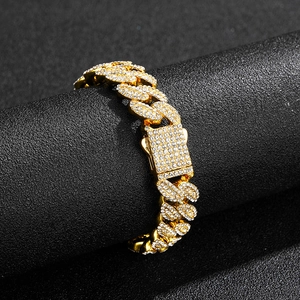 Gros plan du bracelet gourmette plaqué or avec diamants pavés sur un présentoir noir