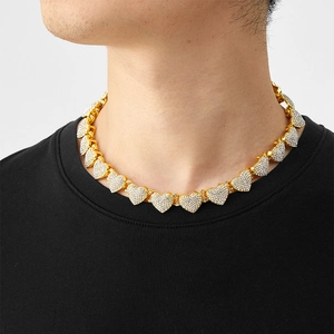 Gros plan d'un collier à maillons cubains dorés avec des cœurs et cristaux blancs