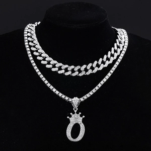 Silver iced out Cuban link chain set with crown letter O pendant on black display