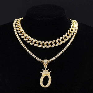 Detail of gold double-layer Cuban link chain and tennis necklace with iced out crown O pendant