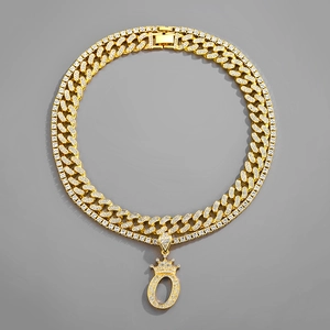 Detail shot of iced-out gold Cuban chain with a crown-topped letter O pendant necklace